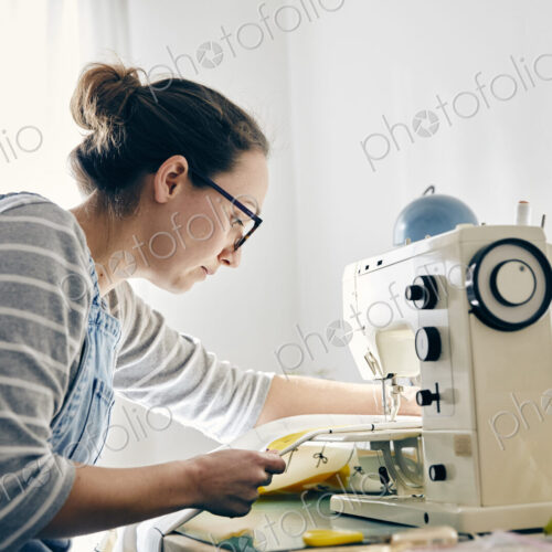 Woman using electric sewing machine to make curtains