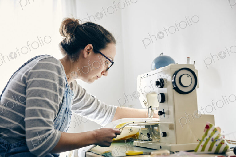 Woman using electric sewing machine to make curtains
