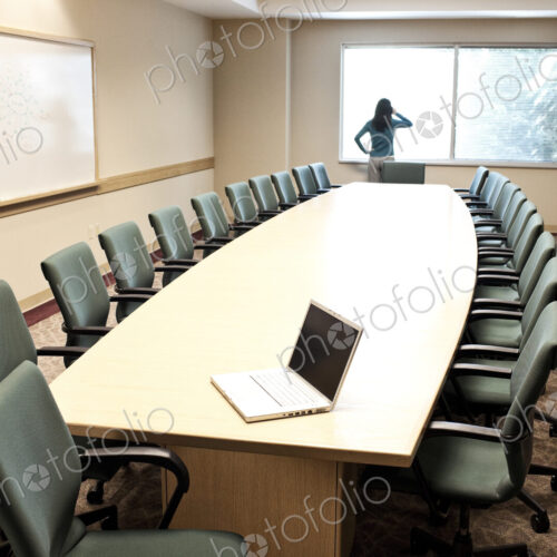 Woman using her phone at a window in a conference room. Woman using her phone at a window in a conference room.