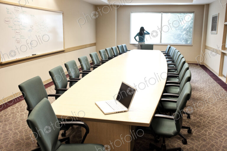Woman using her phone at a window in a conference room.