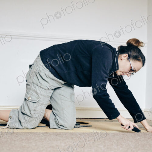 Woman using knife to cut away carpet on floor Woman using knife to cut away carpet on floor