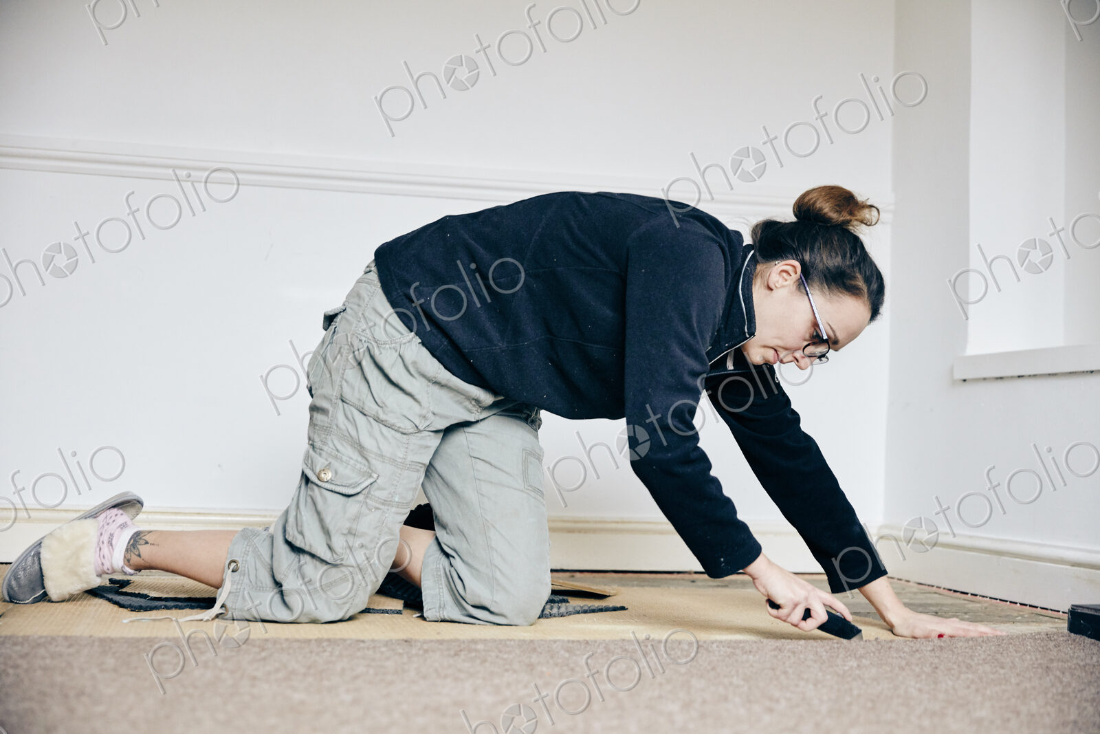 Woman using knife to cut away carpet on floor