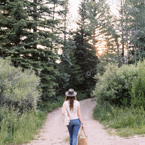 Woman walking along a forest path, carrying a bag. Woman walking along a forest path, carrying a bag.