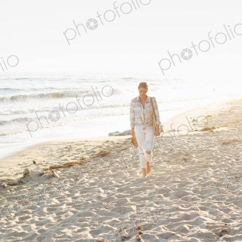 Woman walking along a sandy beach by the ocean.