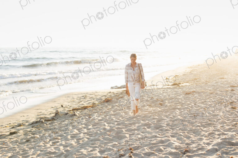 Woman walking along a sandy beach by the ocean.