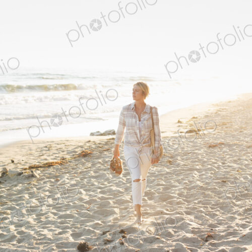 Woman walking along a sandy beach by the ocean.