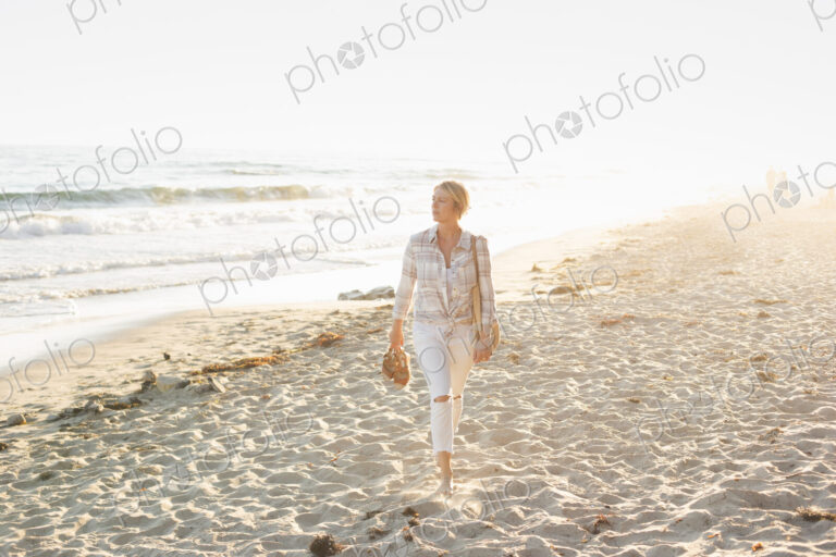 Woman walking along a sandy beach by the ocean.