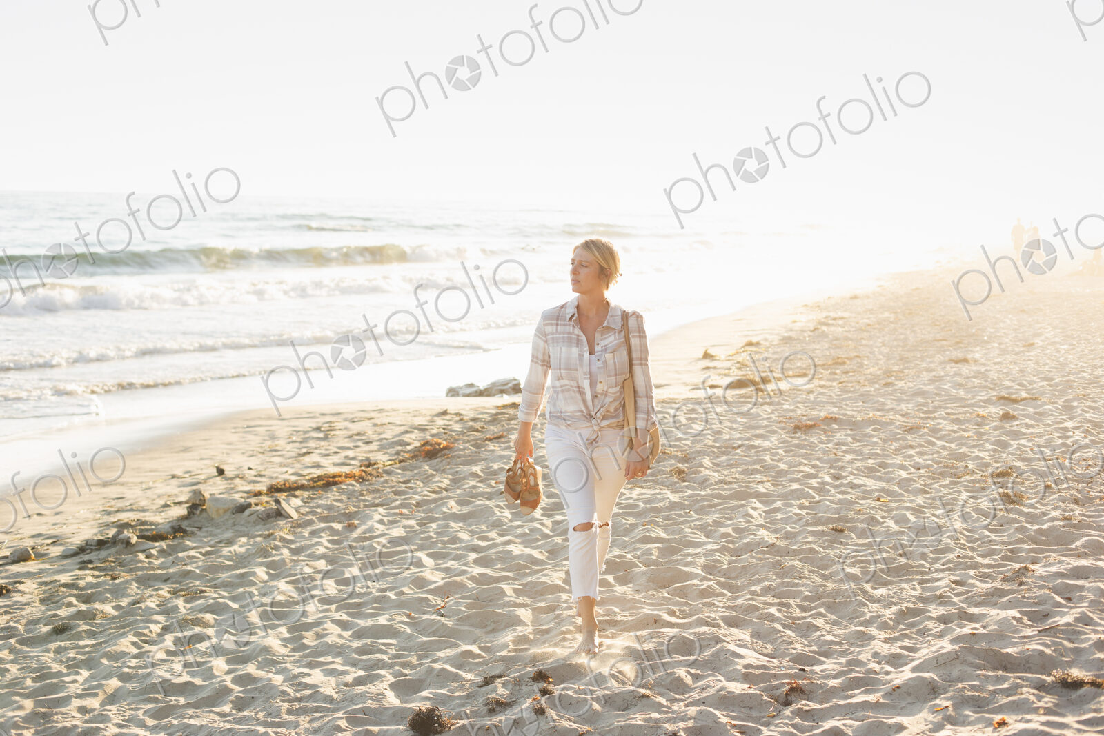 Woman walking along a sandy beach by the ocean.
