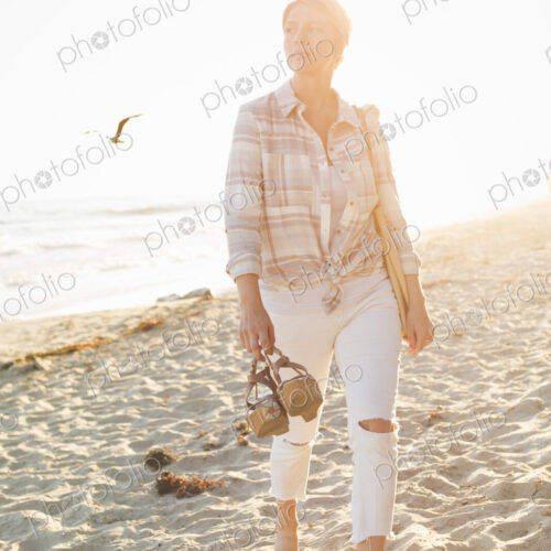 Woman walking along a sandy beach by the ocean. Woman walking along a sandy beach by the ocean.