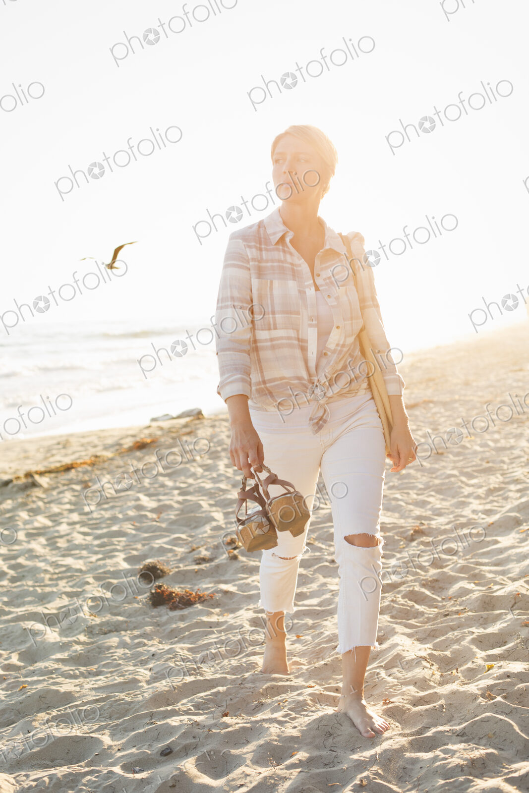 Woman walking along a sandy beach by the ocean.