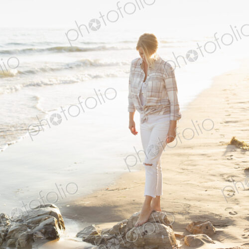 Woman walking along a sandy beach by the ocean. Woman walking along a sandy beach by the ocean.