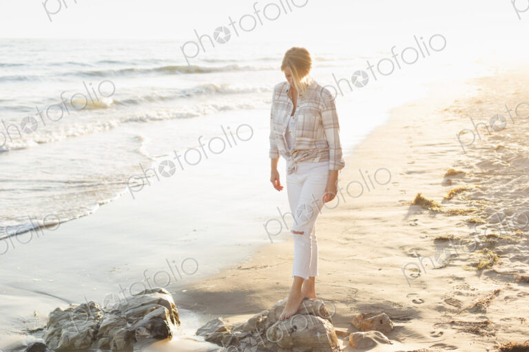 Woman walking along a sandy beach by the ocean.