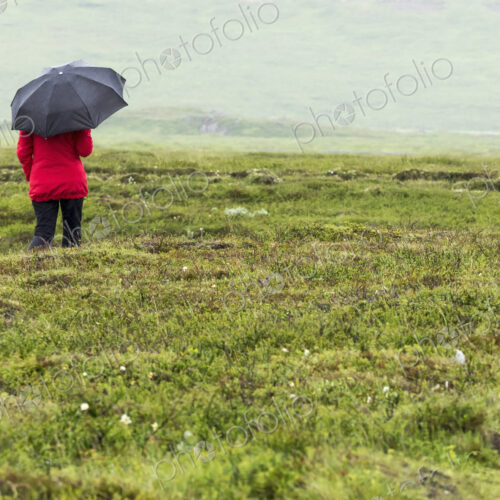 Woman walking in rain with red jacket and black umbrella Woman walking in rain with red jacket and black umbrella