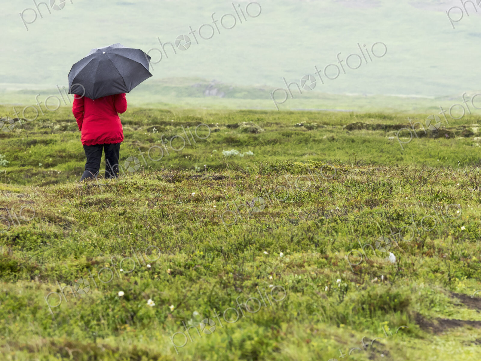 Woman walking in rain with red jacket and black umbrella