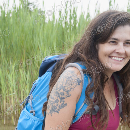 Woman wearing backpack in grass landscape.