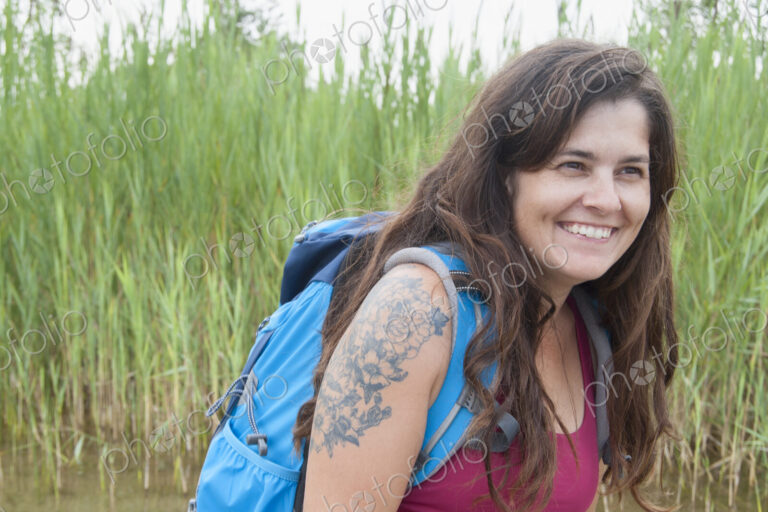 Woman wearing backpack in grass landscape.