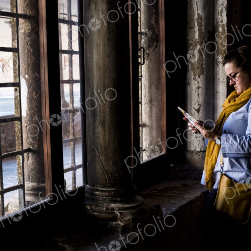 Woman wearing glasses standing at window of a historic building in Venice, Veneto, Italy.