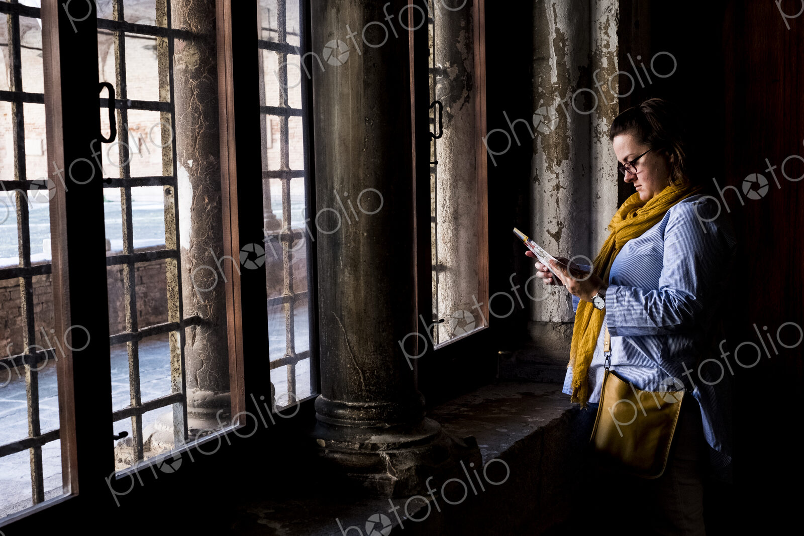 Woman wearing glasses standing at window of a historic building in Venice, Veneto, Italy.
