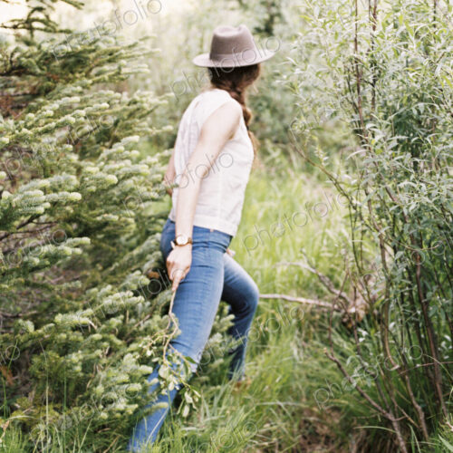 Woman wearing jeans and a hat walking through a forest. Woman wearing jeans and a hat walking through a forest.