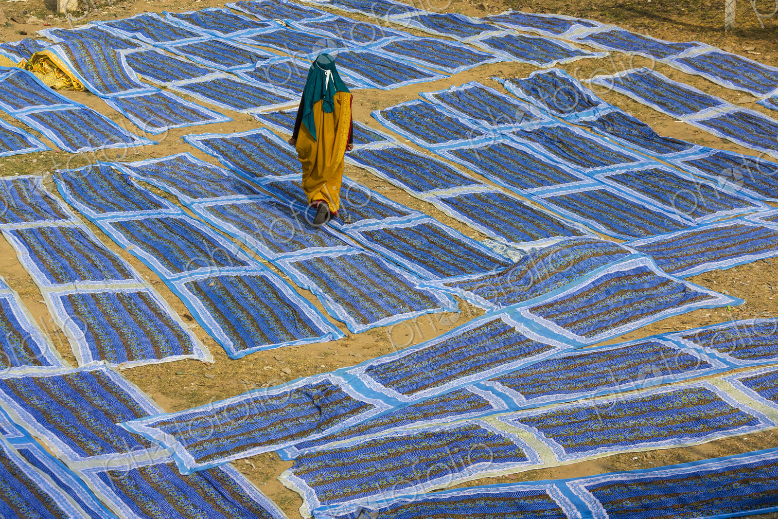 Woman wearing sari walking across blue textiles