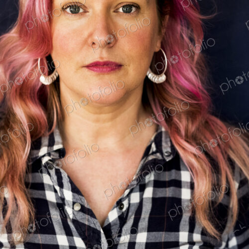 Woman with long blond wavy hair with pink streaks and checked shirt
