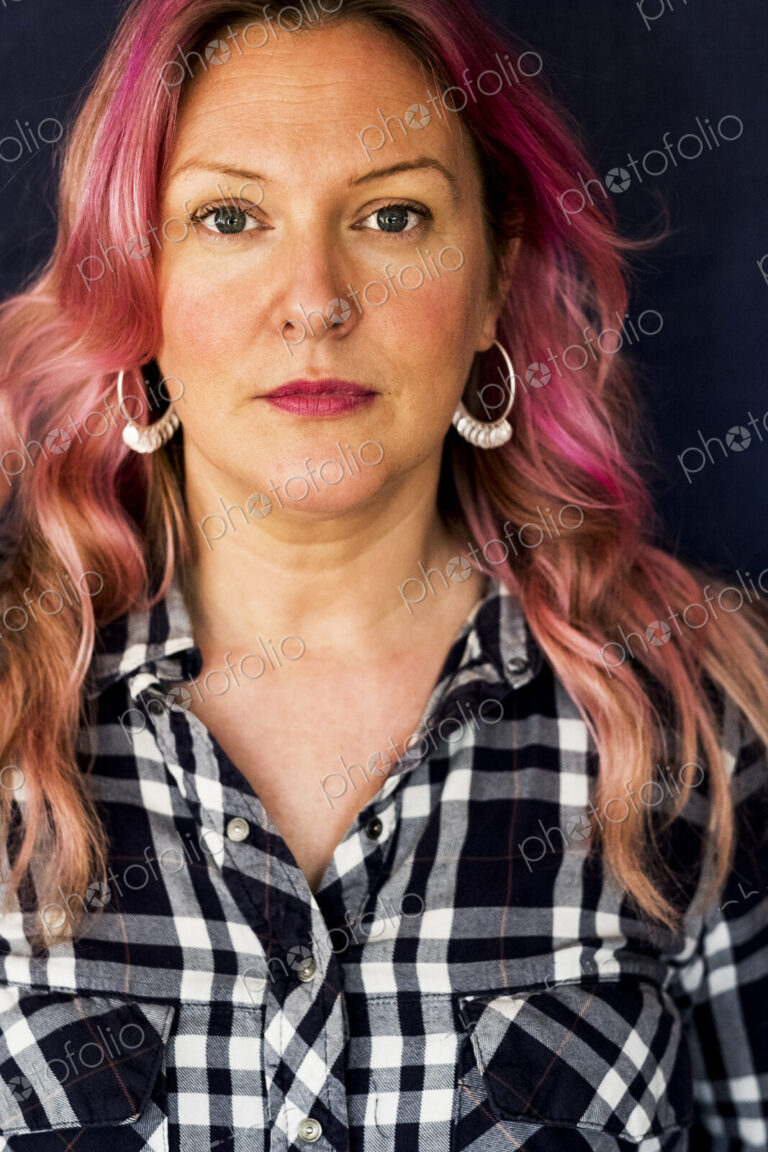 Woman with long blond wavy hair with pink streaks and checked shirt