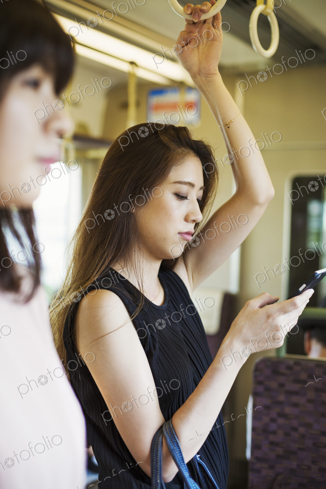 Woman with long brown hair traveling on public transport, using mobile phone.