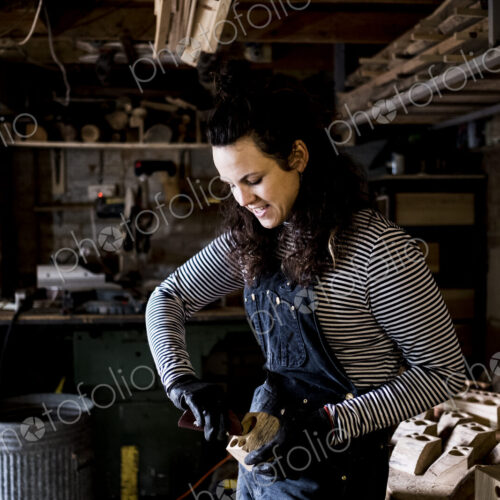 Woman with long brown hair wearing dungarees, working in wood workshop. Woman with long brown hair wearing dungarees, working in wood workshop.