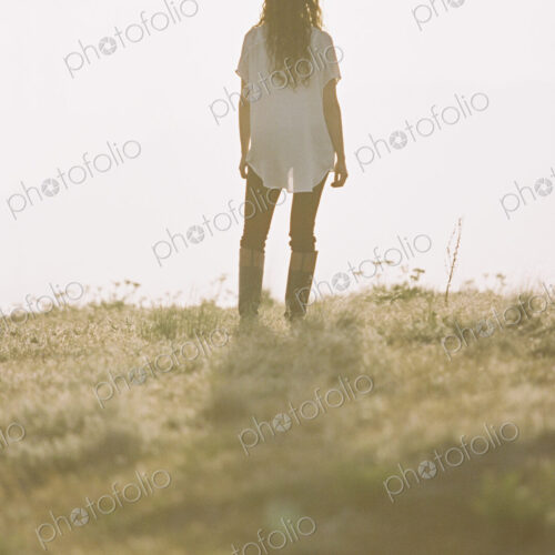 Woman with long curly hair standing looking towards the horizon.