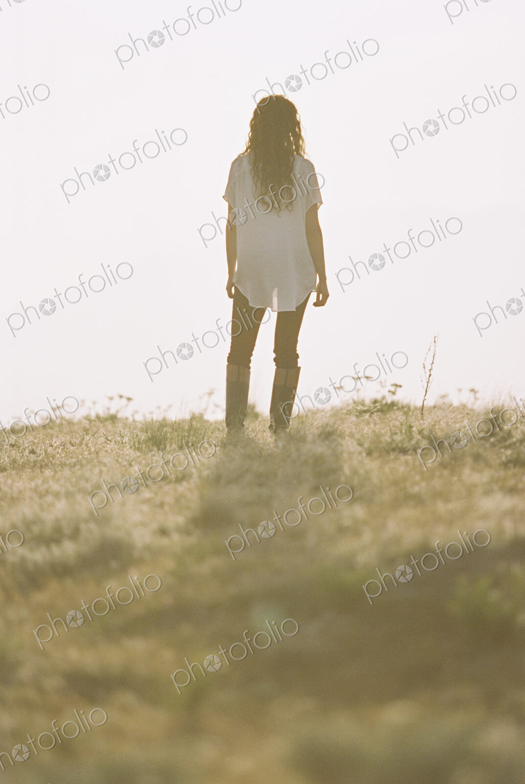 Woman with long curly hair standing looking towards the horizon.