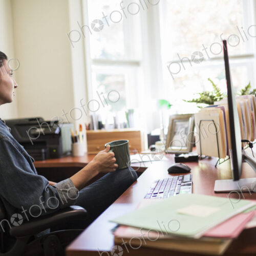 Woman working on a desktop computer in her home office. Woman working on a desktop computer in her home office.