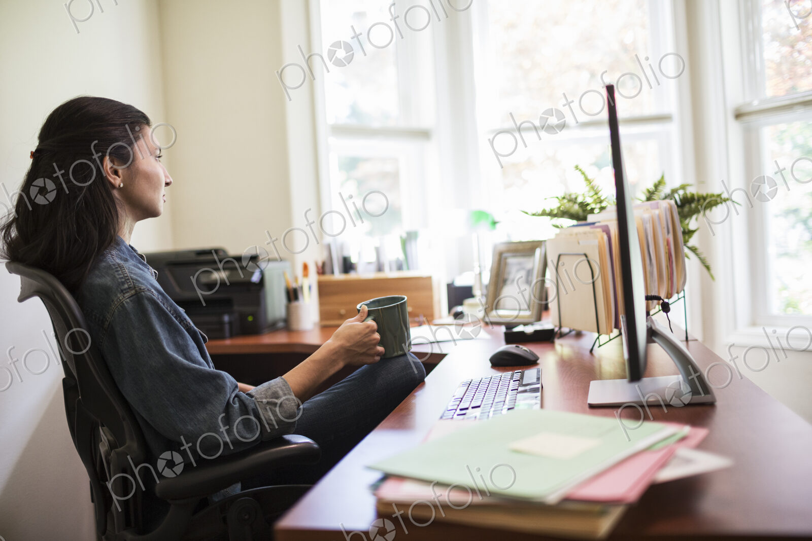 Woman working on a desktop computer in her home office.