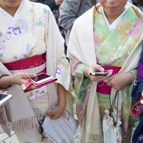 Women wearing traditional Japanese kimonos holding smartphones. Women wearing traditional Japanese kimonos holding smartphones.