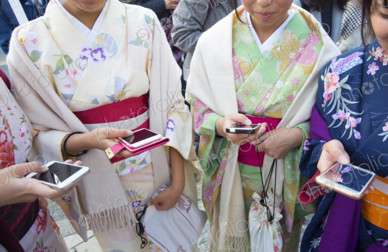 Women wearing traditional Japanese kimonos holding smartphones.