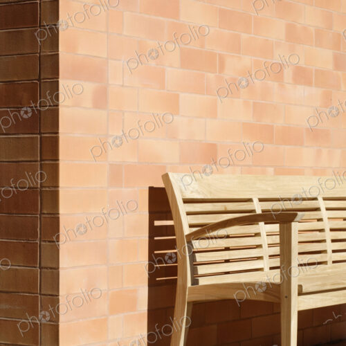 Wooden Bench Against Corner of Brick Building Wooden Bench Against Corner of Brick Building