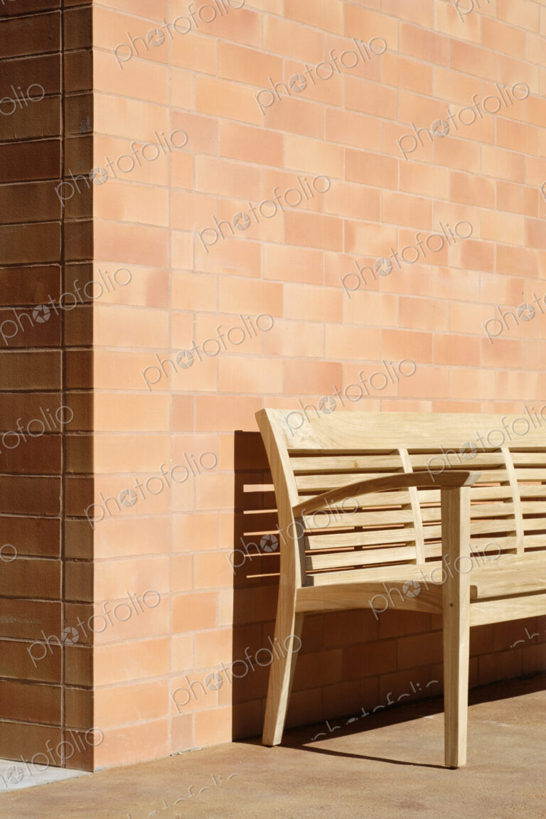 Wooden Bench Against Corner of Brick Building