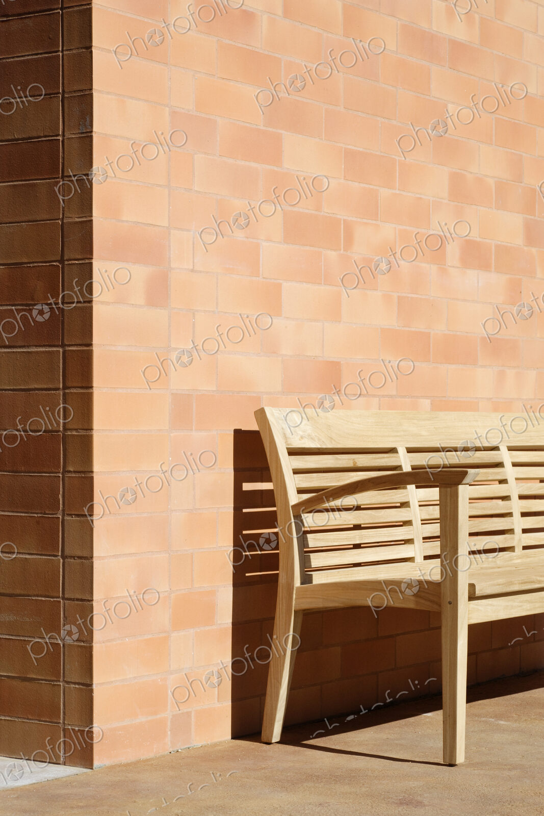 Wooden Bench Against Corner of Brick Building