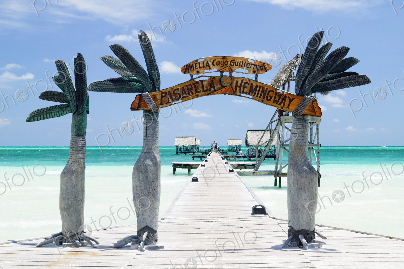 Wooden arch entrance to a pier in tropical ocean.
