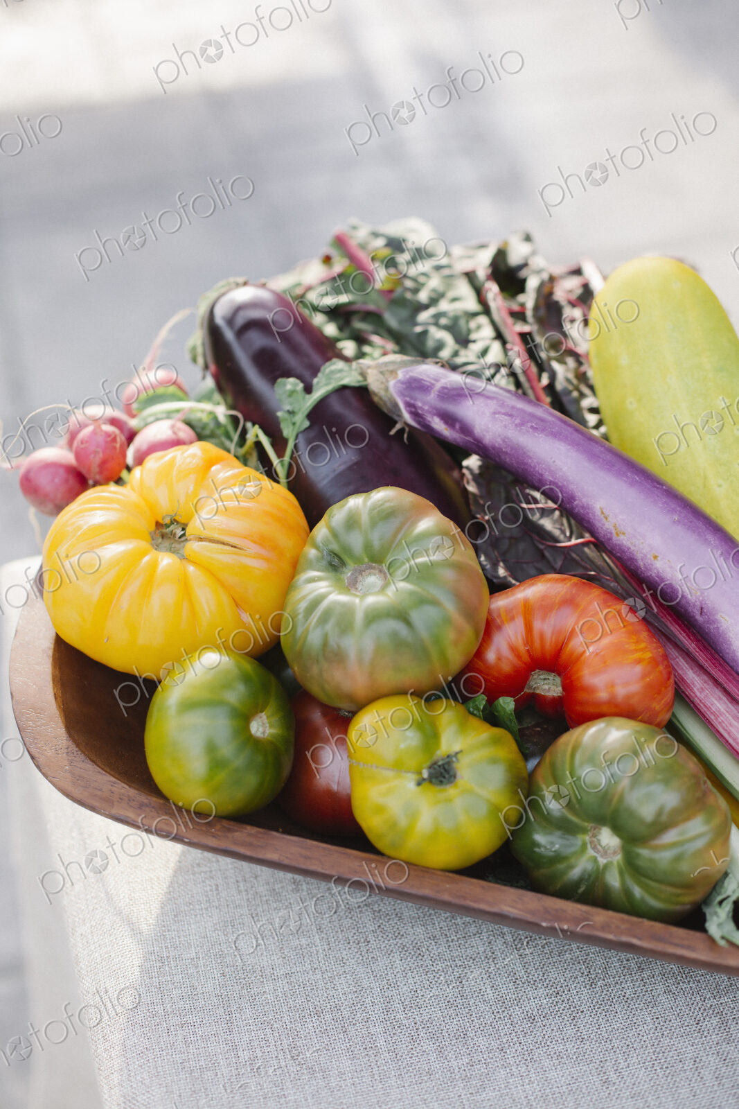 Wooden bowl with fresh vegetables standing on a table.