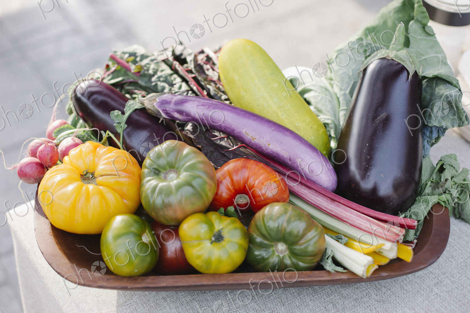 Wooden bowl with fresh vegetables standing on a table.