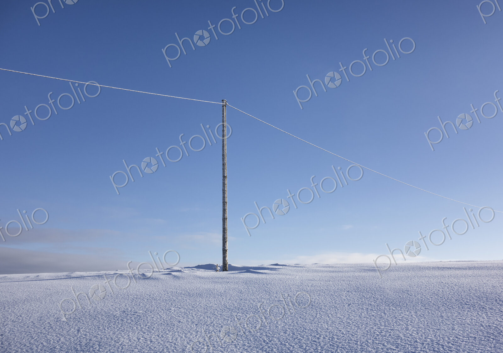 Wooden electric pole on empty snow covered landscape. Electrical industry, power line.