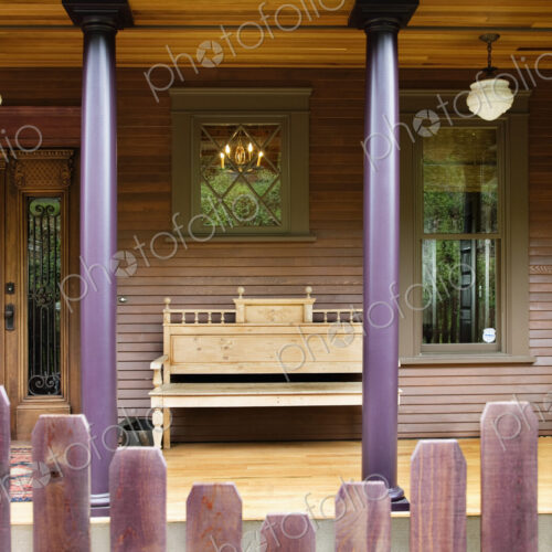 Wooden fence and house porch with columns and bench. Wooden fence and house porch with columns and bench.