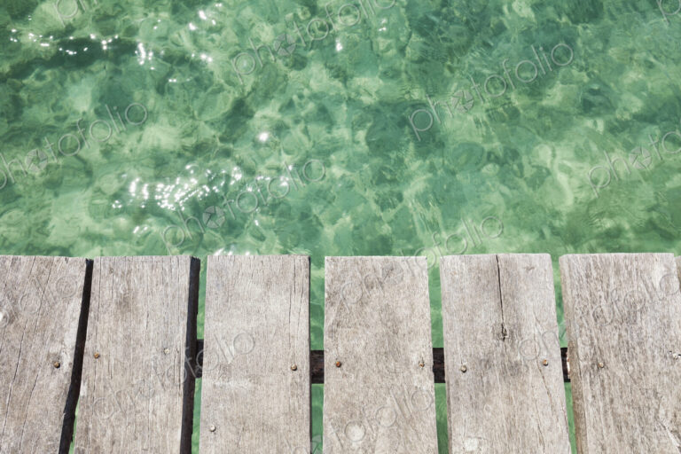 Wooden pier over shallow clear turquoise blue water