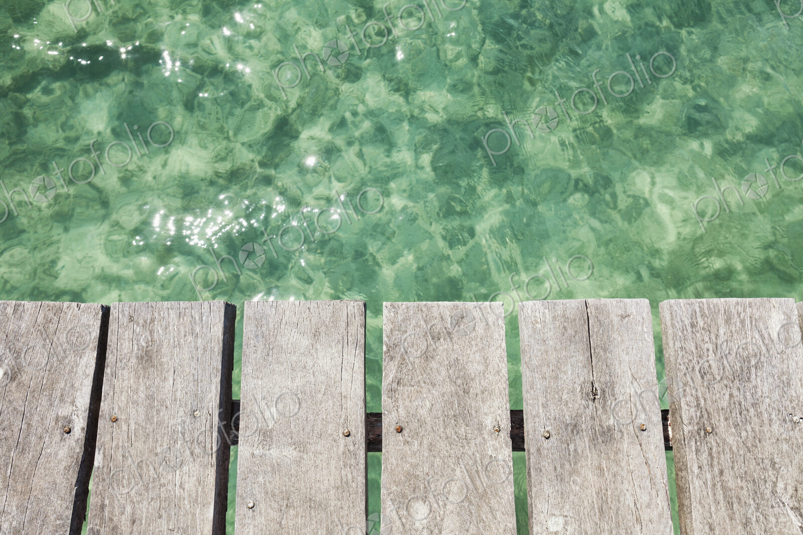 Wooden pier over shallow clear turquoise blue water