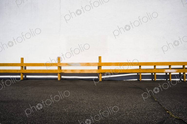 Wooden railing over asphalt.