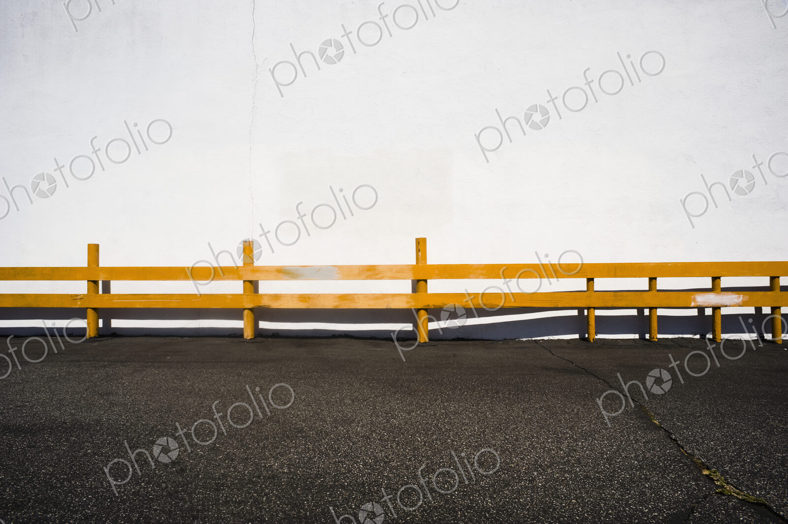 Wooden railing over asphalt.