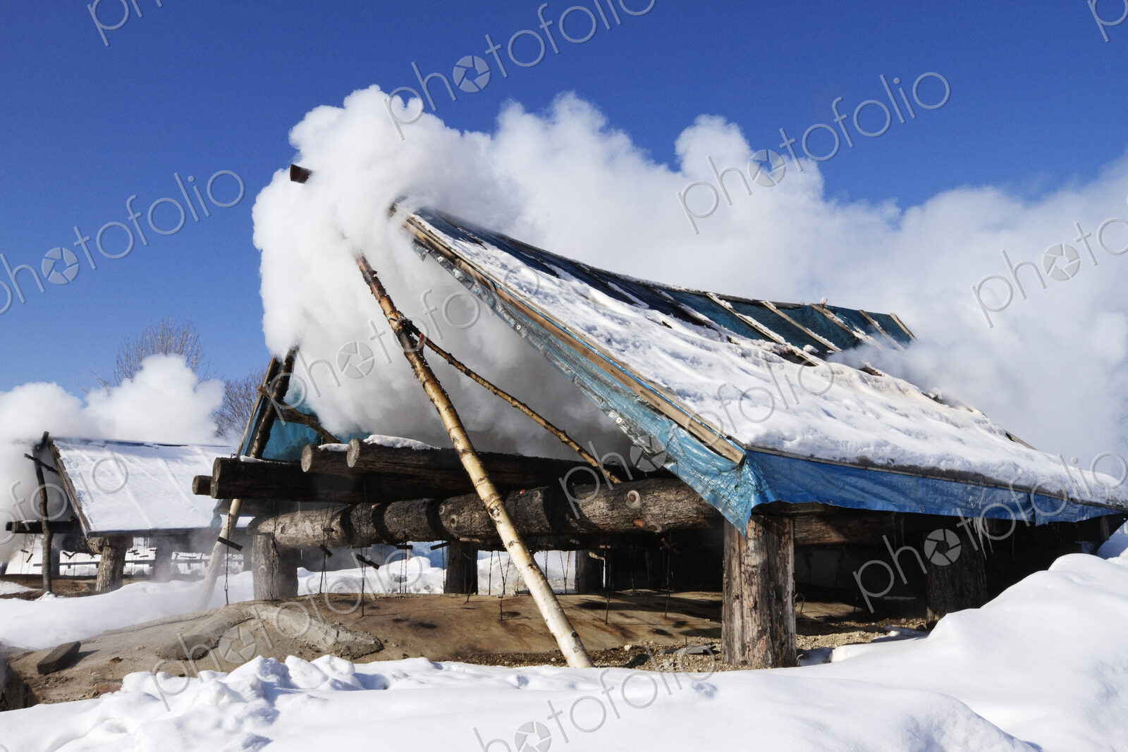 Wooden shack covered with clouds in snow.