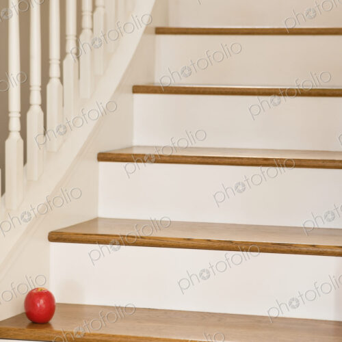 Wooden staircase with banister and red apple.