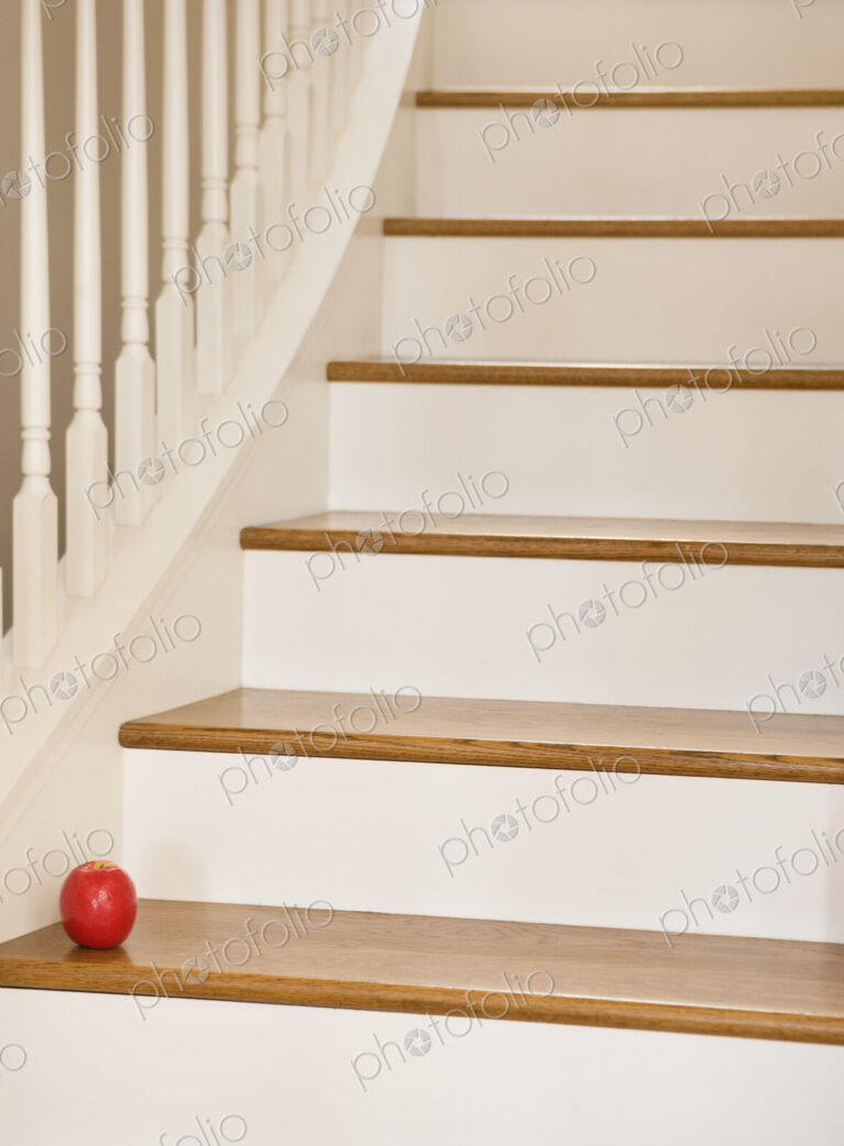 Wooden staircase with banister and red apple.