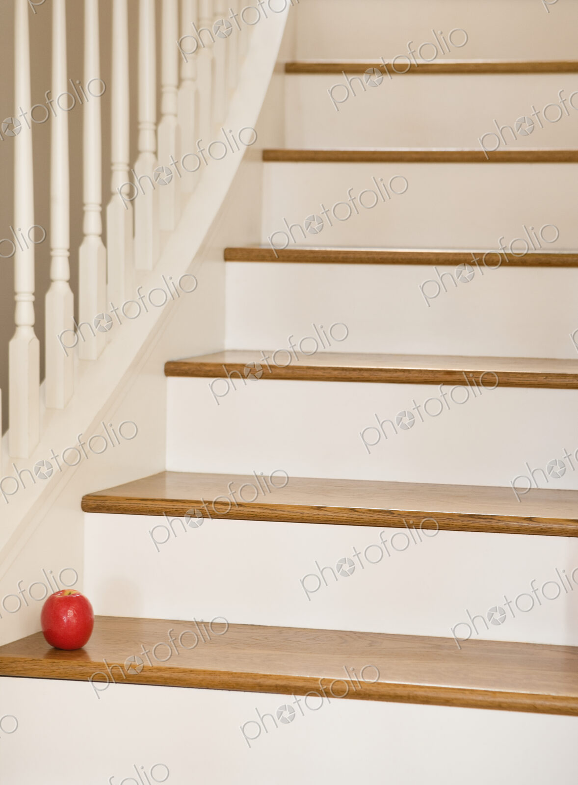 Wooden staircase with banister and red apple.